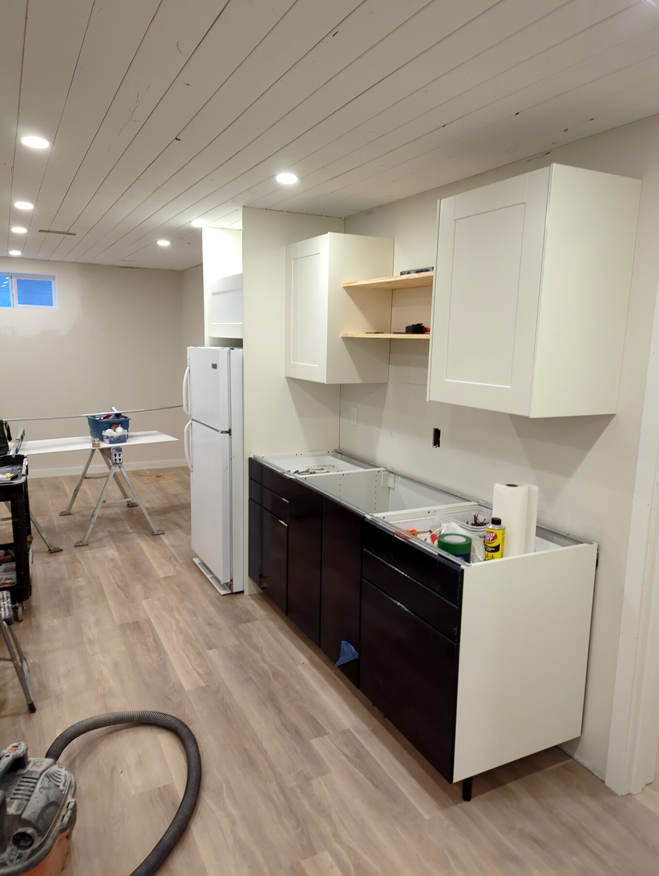 Basement room with finished flooring, cabinetry, and a vacuum on site