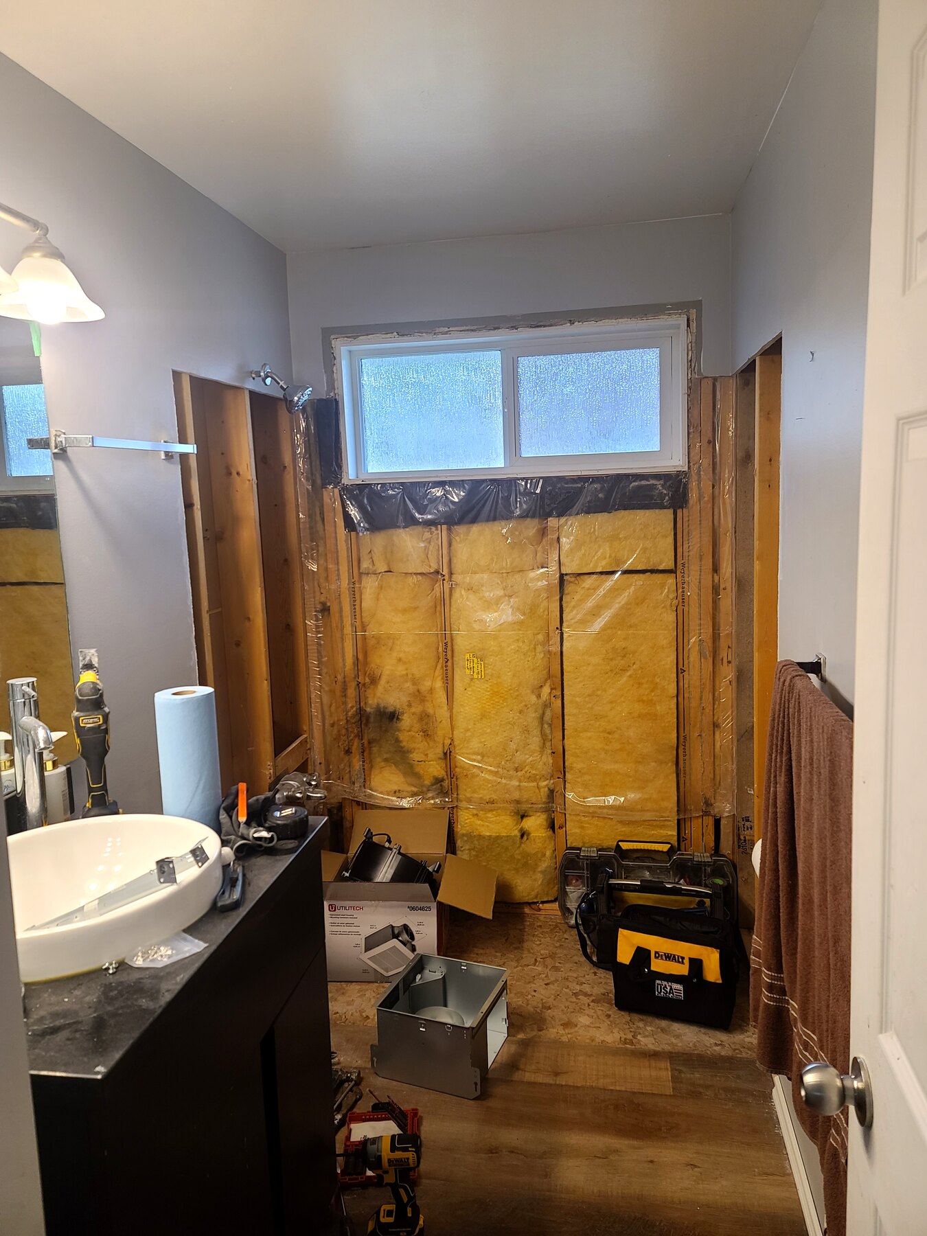 Existing bathroom with opened wall and exposed framing