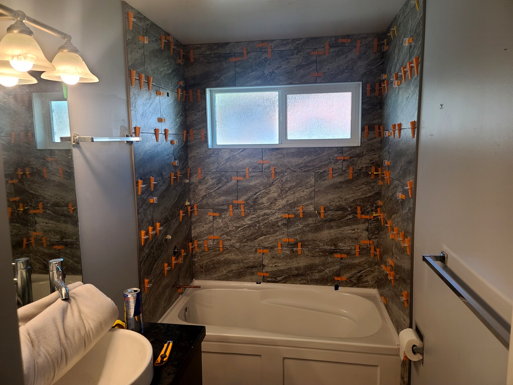Bathroom tub surround with tile installation underway around the window