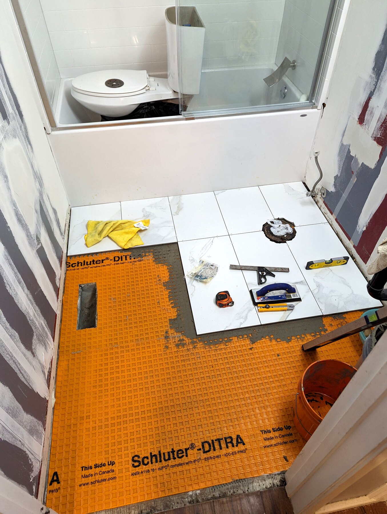 Bathroom floor and wall with orange waterproofing membrane in place