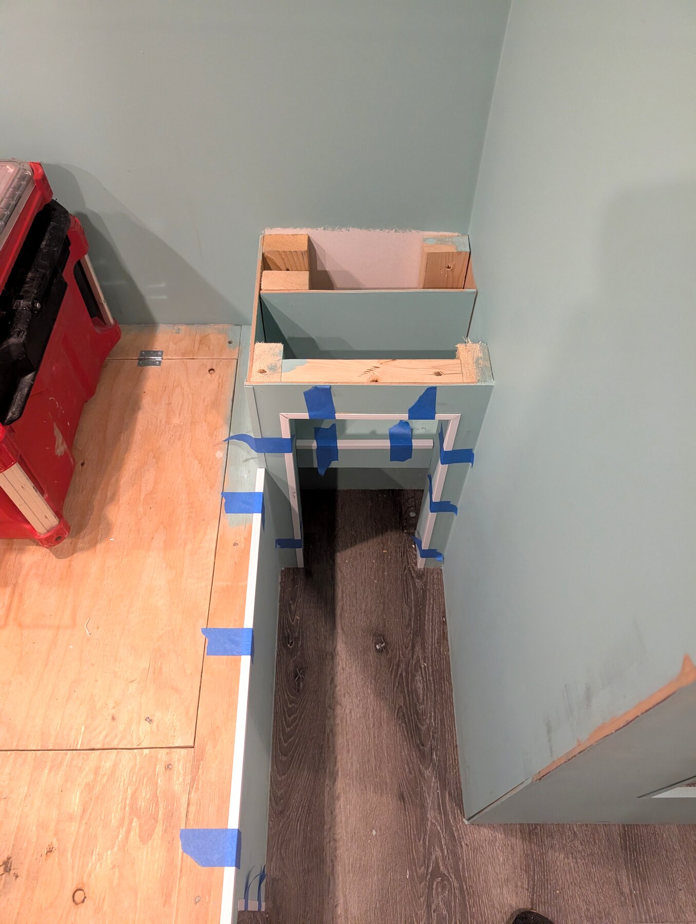 Built-in desk and storage work with masking tape and tools visible