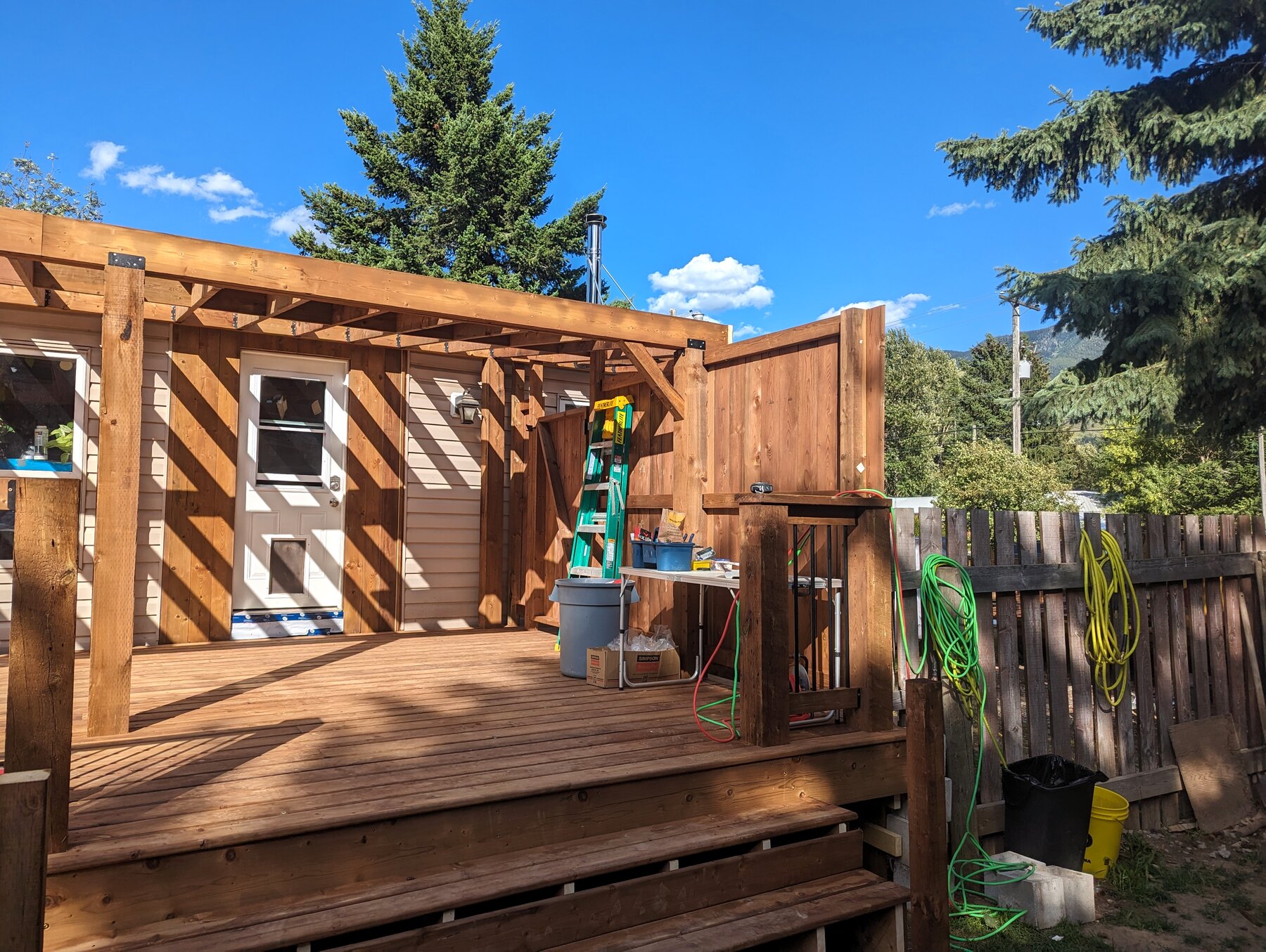 Completed wood deck with pergola-style framing and privacy fencing