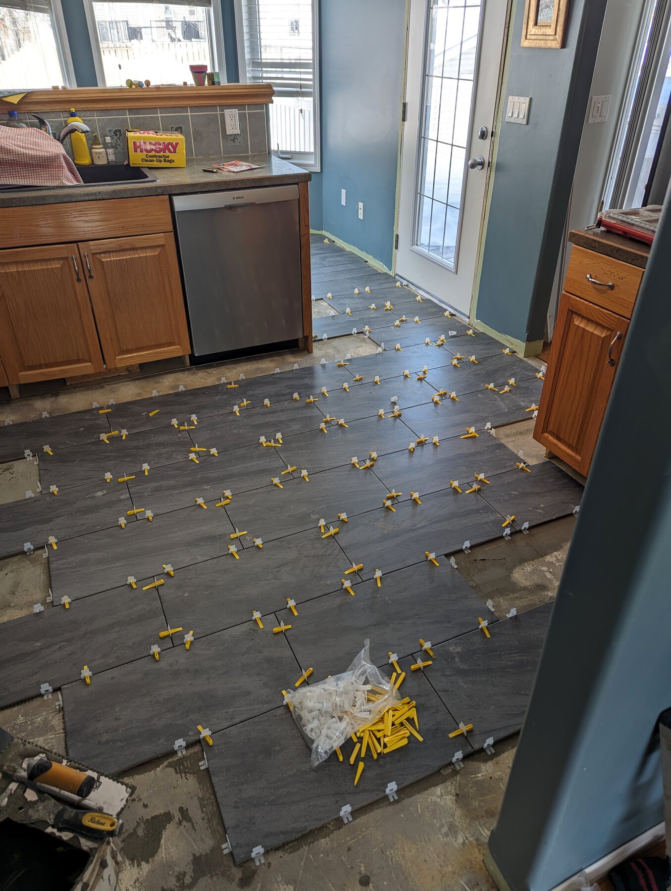 Floor tile installation with levelling clips in a kitchen area