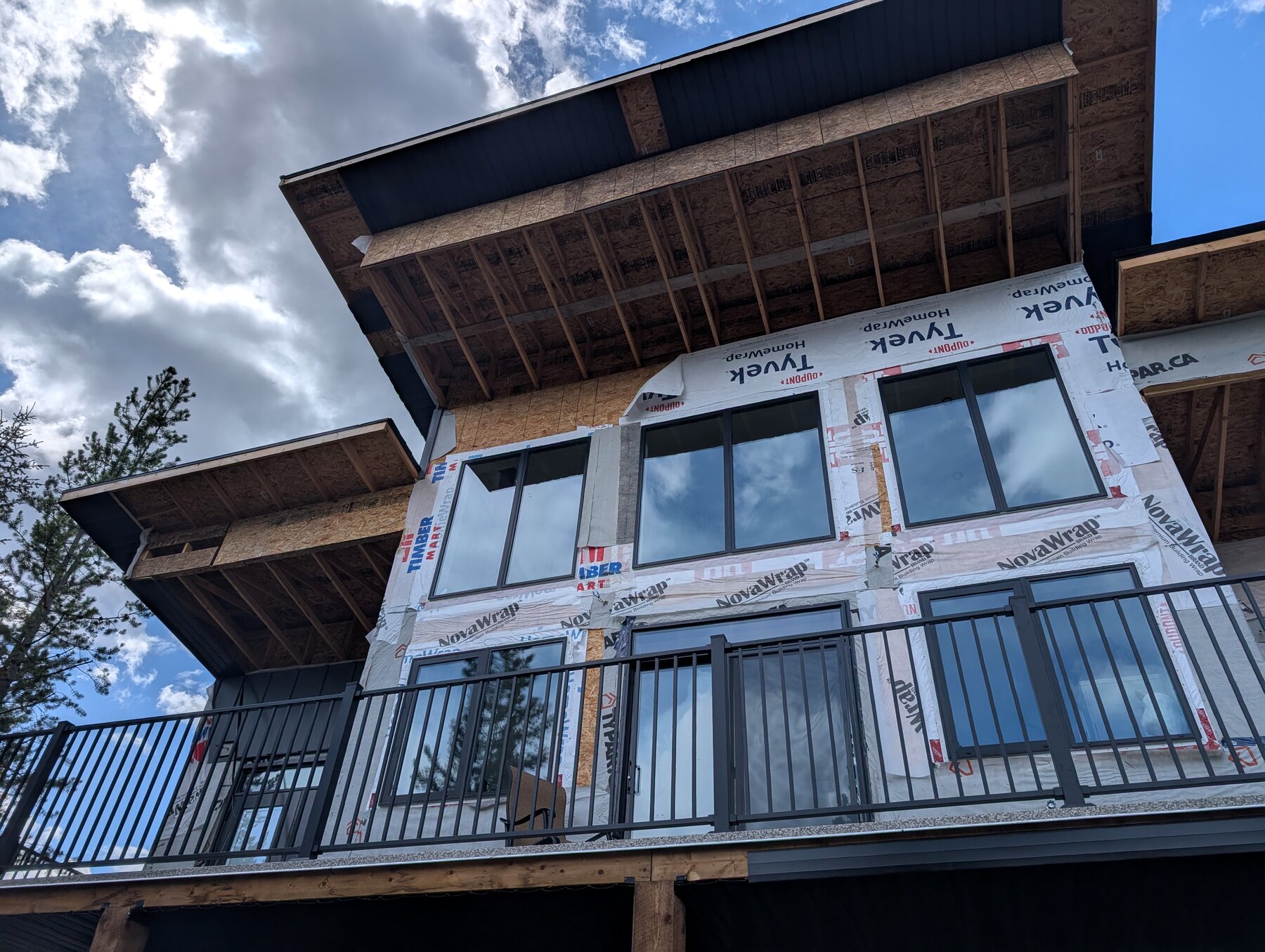 New-build exterior viewed from below with unfinished roof overhangs and balcony