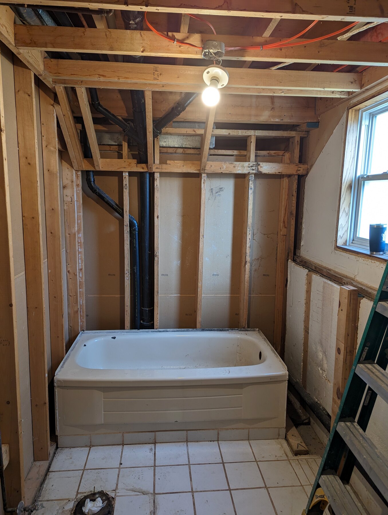 Bathroom shower area with tub, open framing, and exposed ceiling
