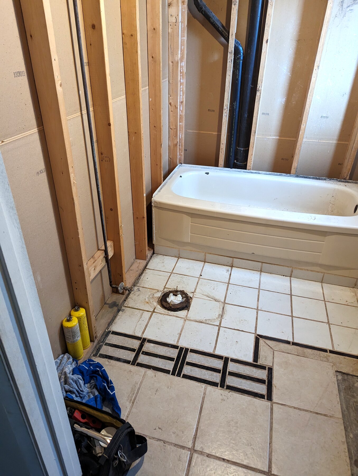 Bathroom tub and floor tile work with open wall framing