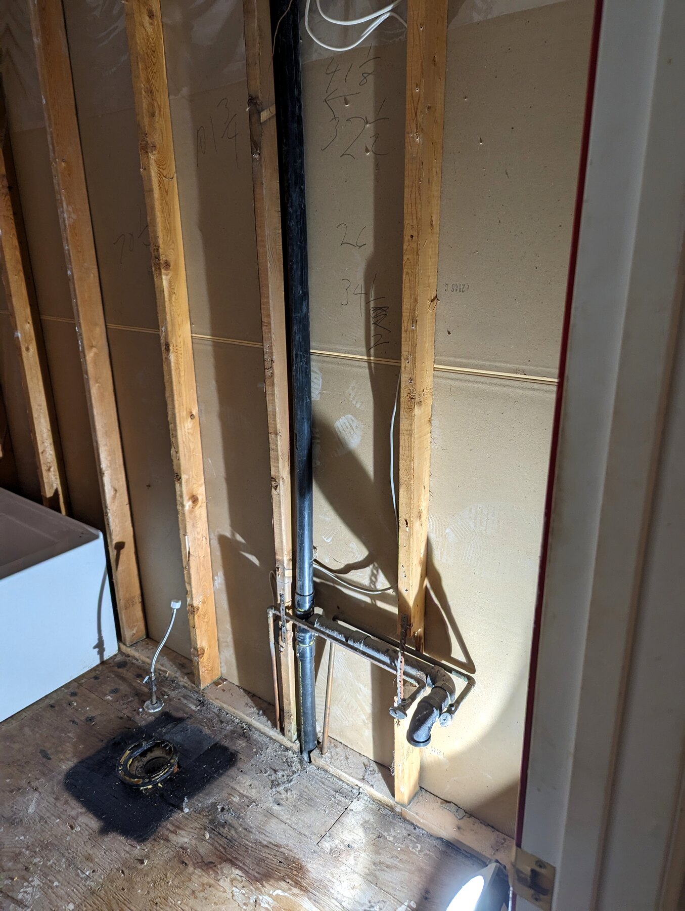 Bathroom shower area with exposed plumbing and wall framing