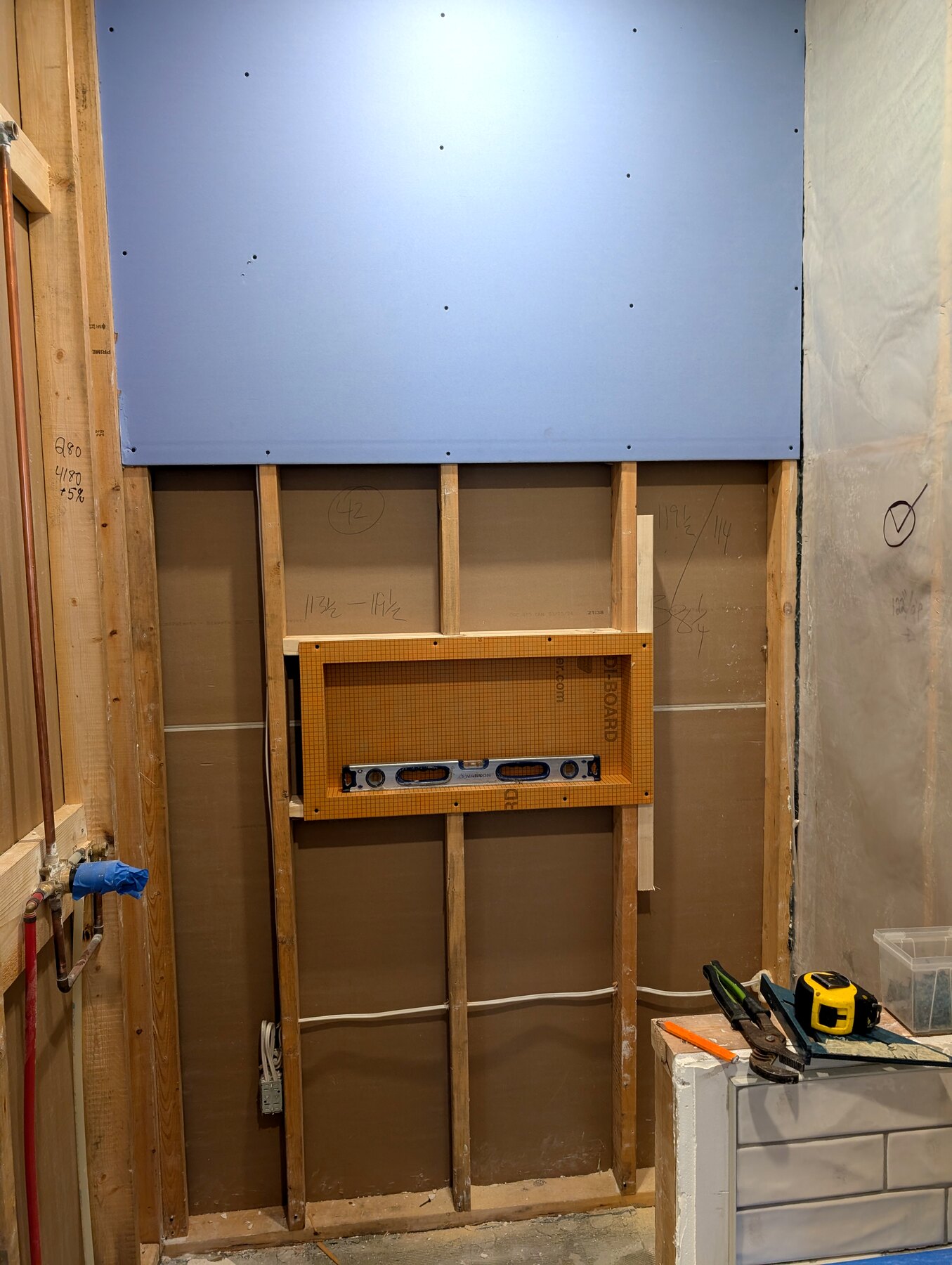 Bathroom shower wall with board and a framed storage niche