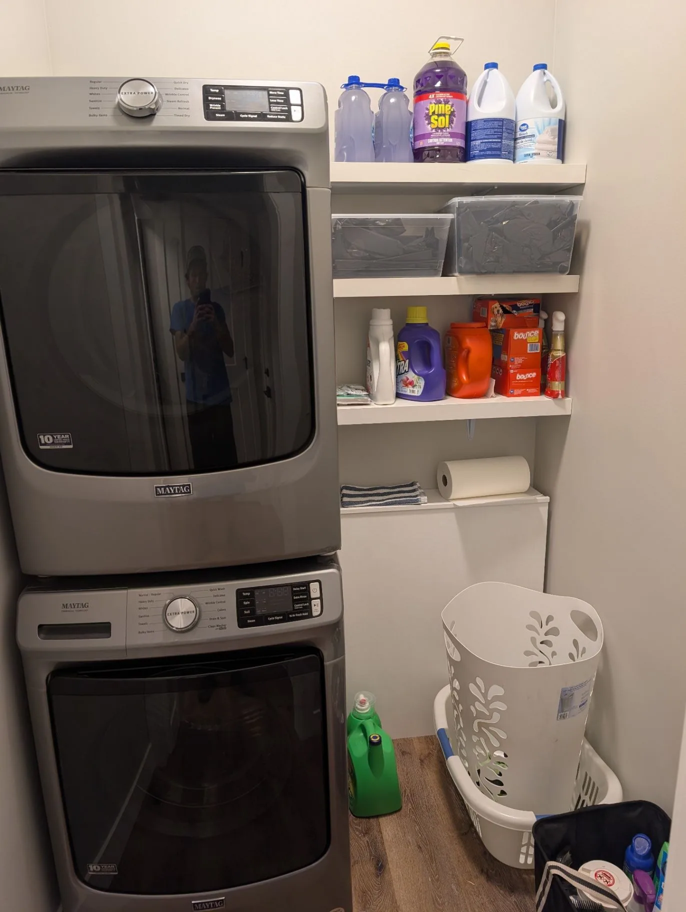 Basement laundry area with stacked washer and dryer and storage shelves