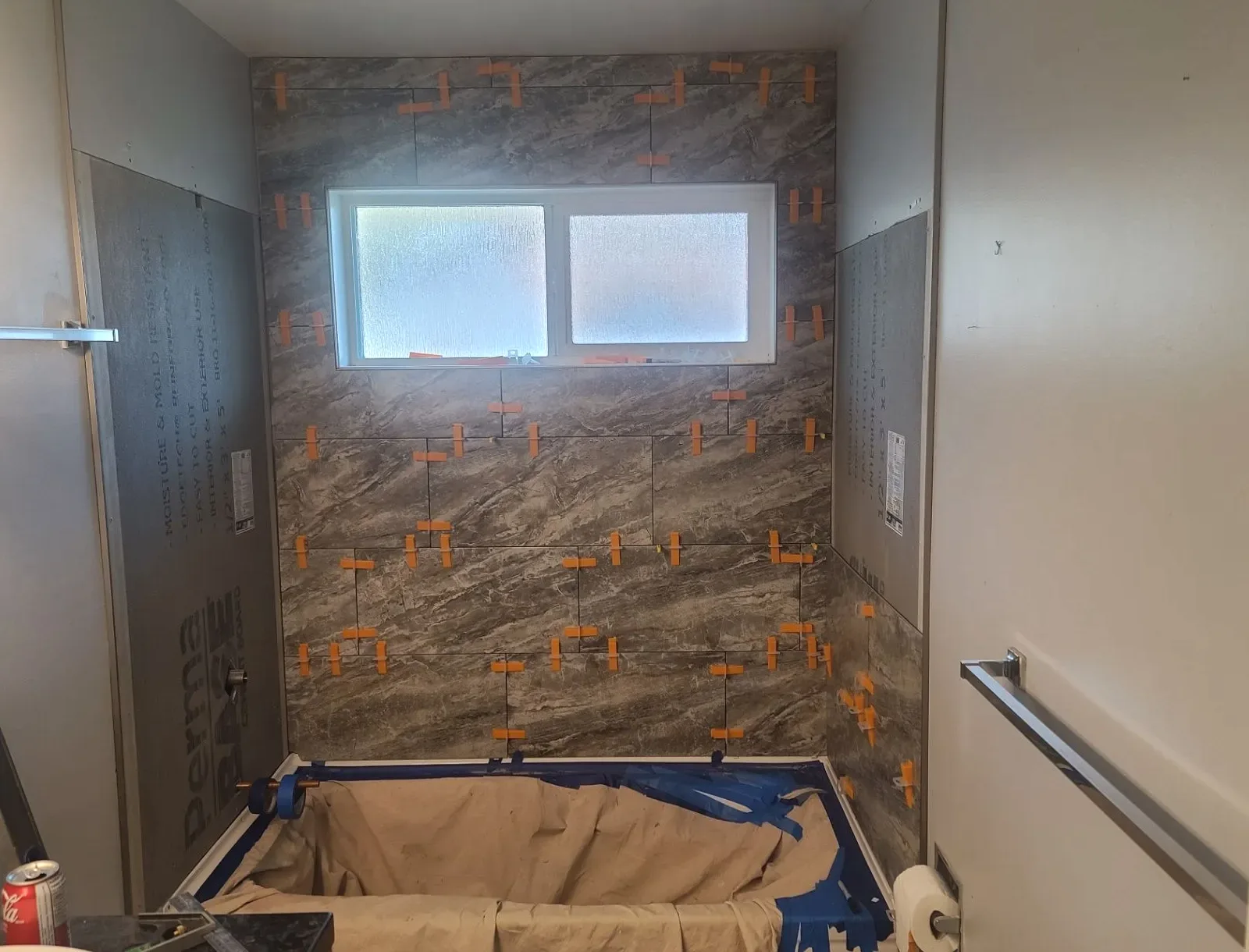 Bathroom wall tile set around a frosted window with orange spacers still visible