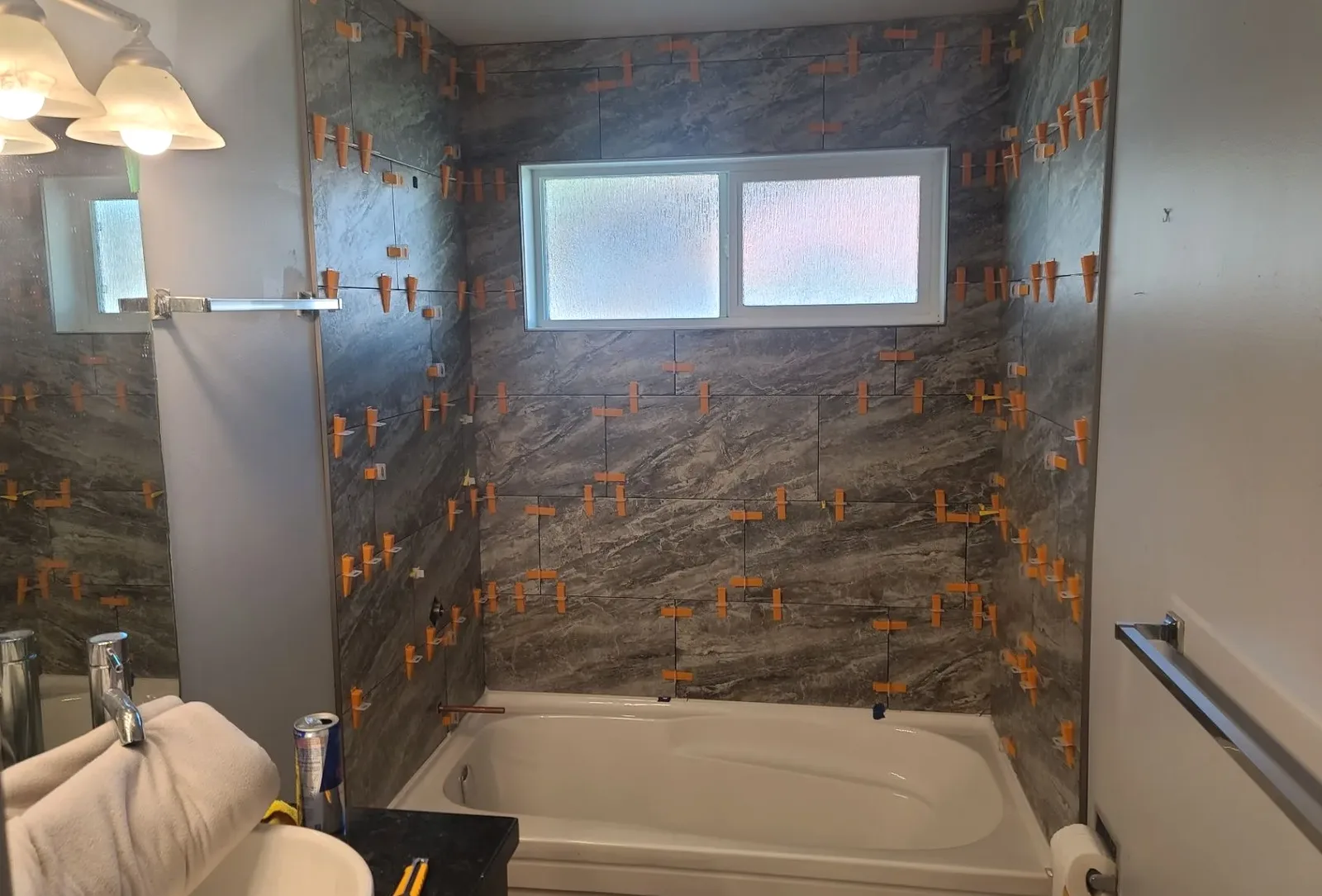 Bathroom tub surround with large-format wall tiles and installation spacers