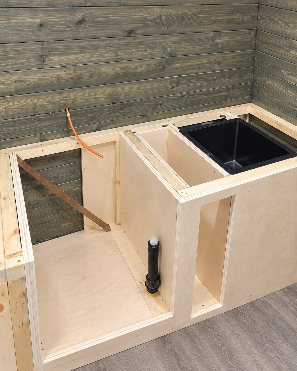 Cabinet carcasses and counter framing with an undermount sink cut-out and plumbing rough-in, mid-build
