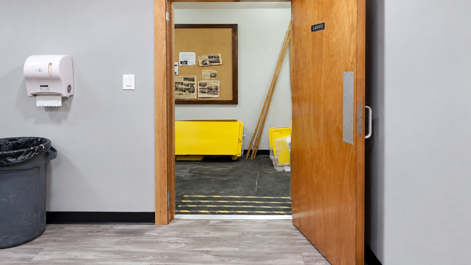 New laminate flooring through a hallway and a trimmed wooden door opening in a commercial or community building
