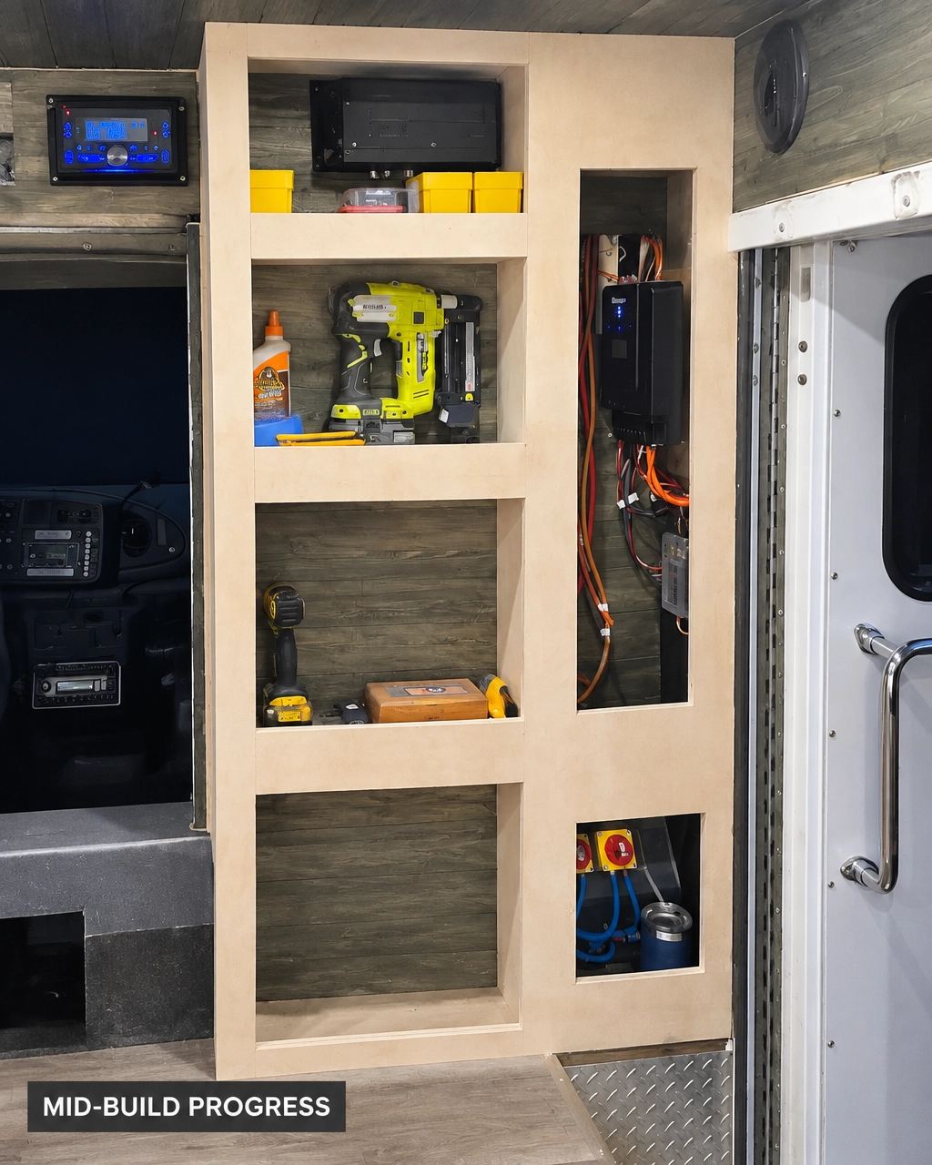 Custom built-in shelving and storage wall with cubbies and a service chase over wood-plank panelling, mid-build