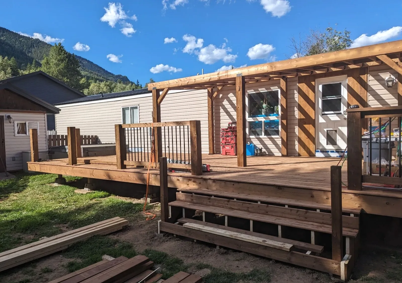Residential deck and fence build with unfinished stairs, rail posts, and loose boards on site