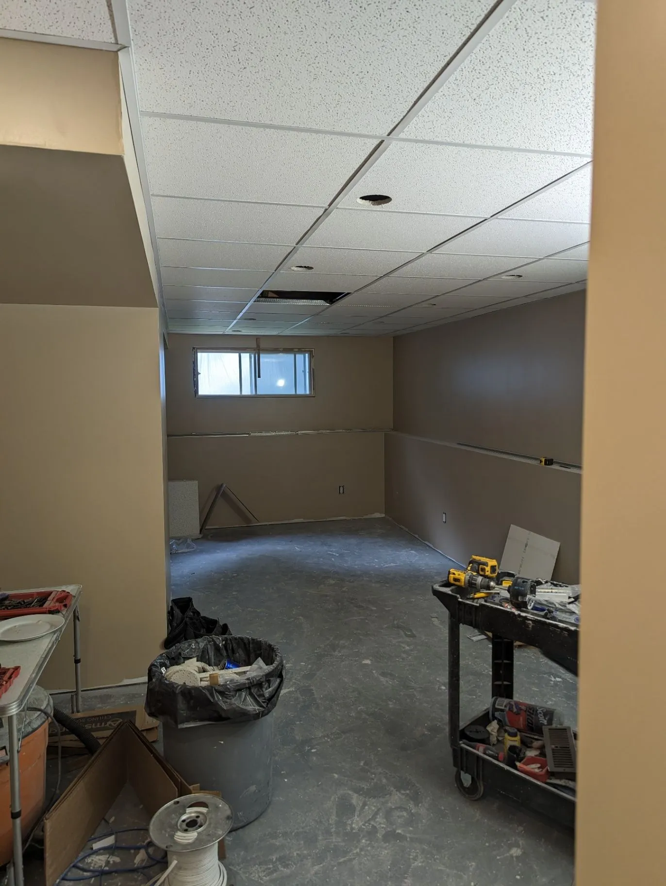 Basement room with ceiling grid and finishing tools