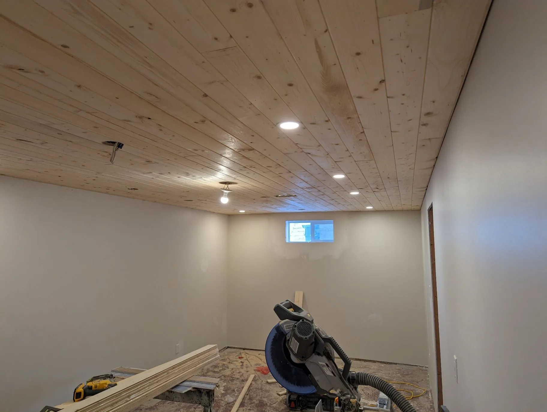 Basement room with finished ceiling and tools on site