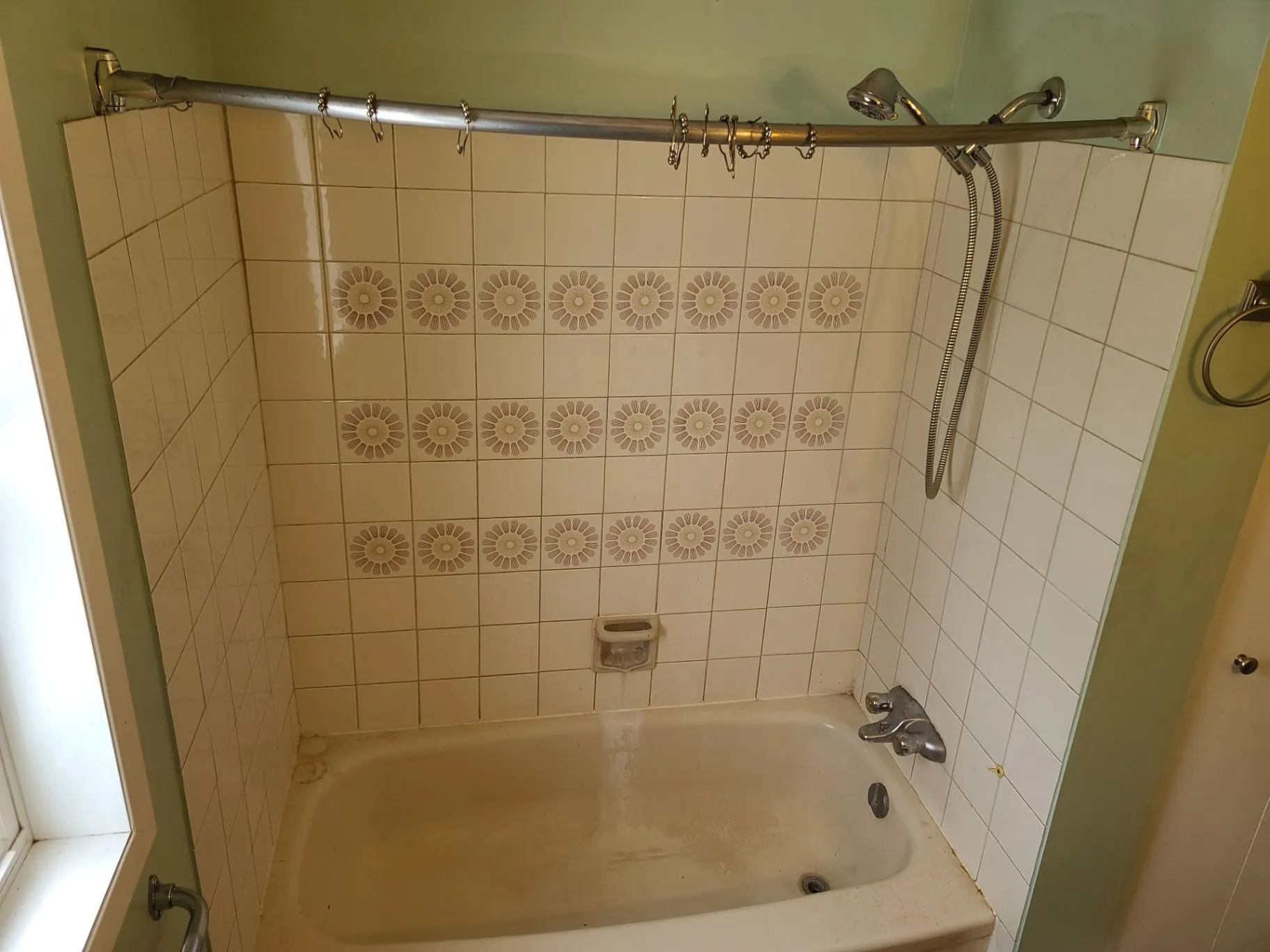 Existing bathtub surround with green daisy-pattern tile