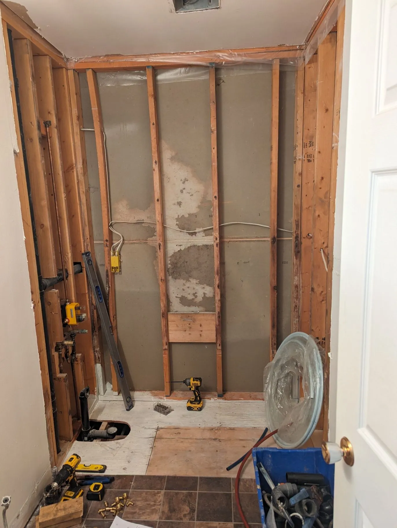 Bathroom wall opened to framing around the tub area