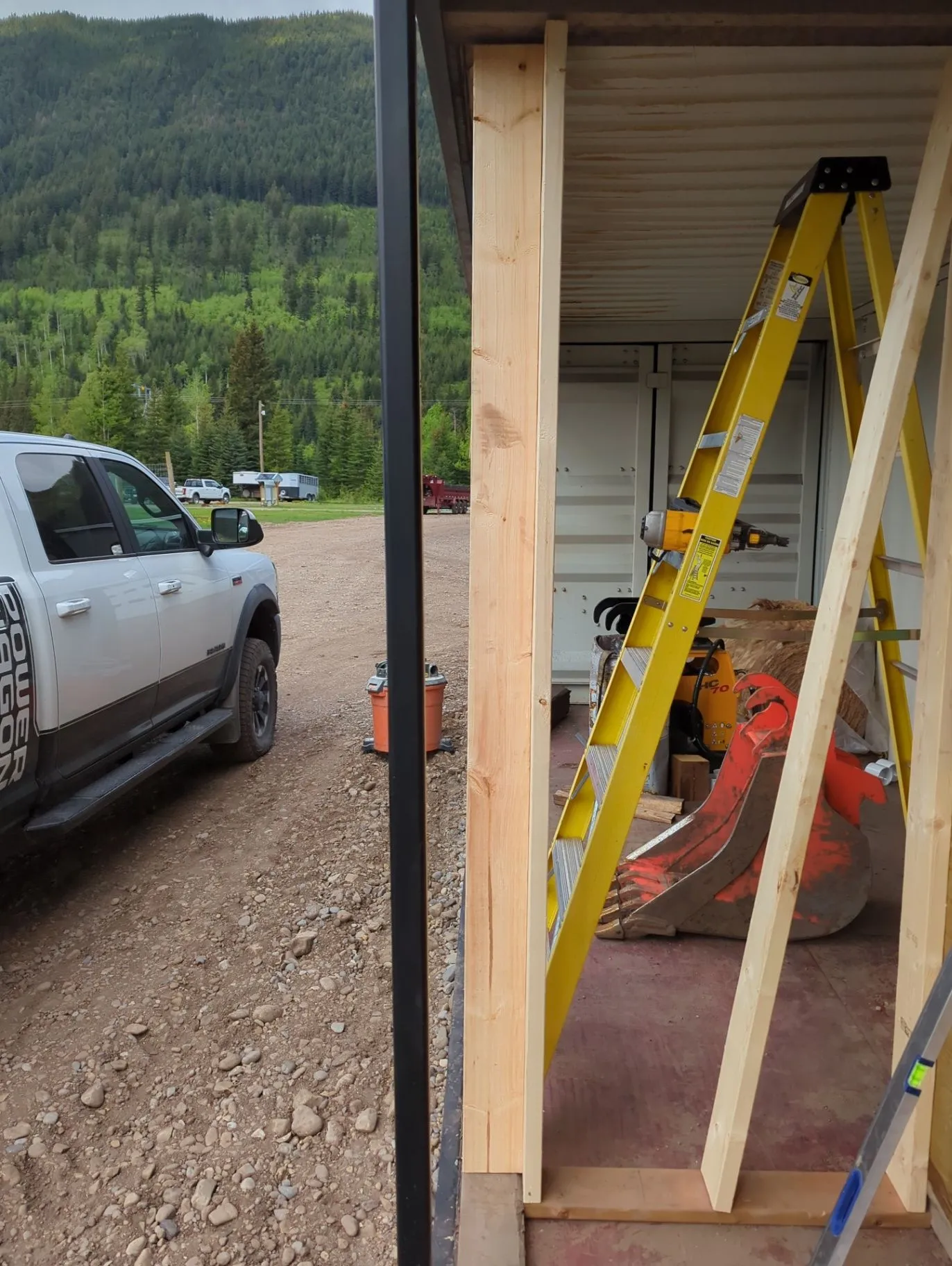 Exterior framing and ladder work beside a residential structure