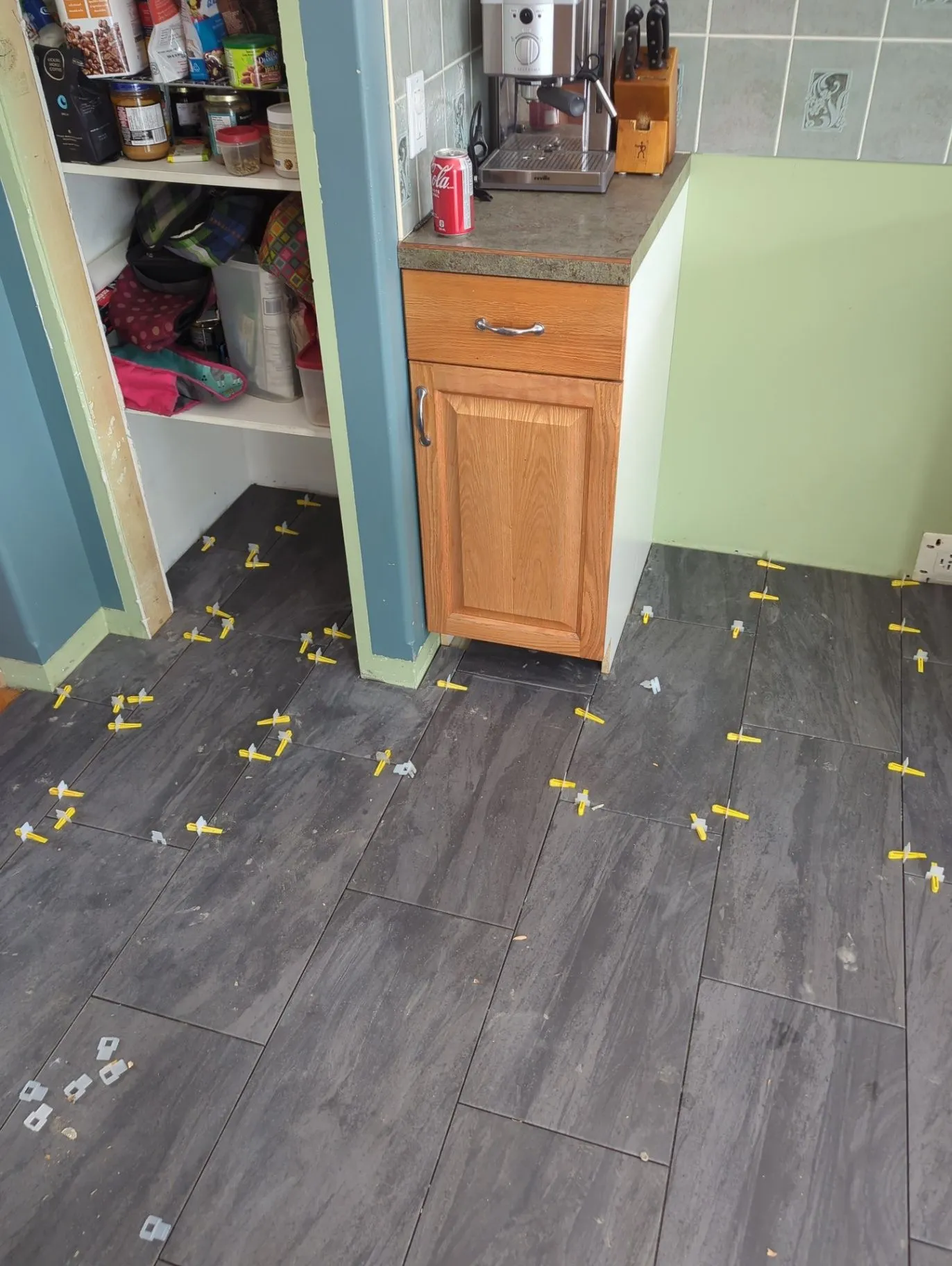 Floor tiles being installed with spacers in a kitchen area