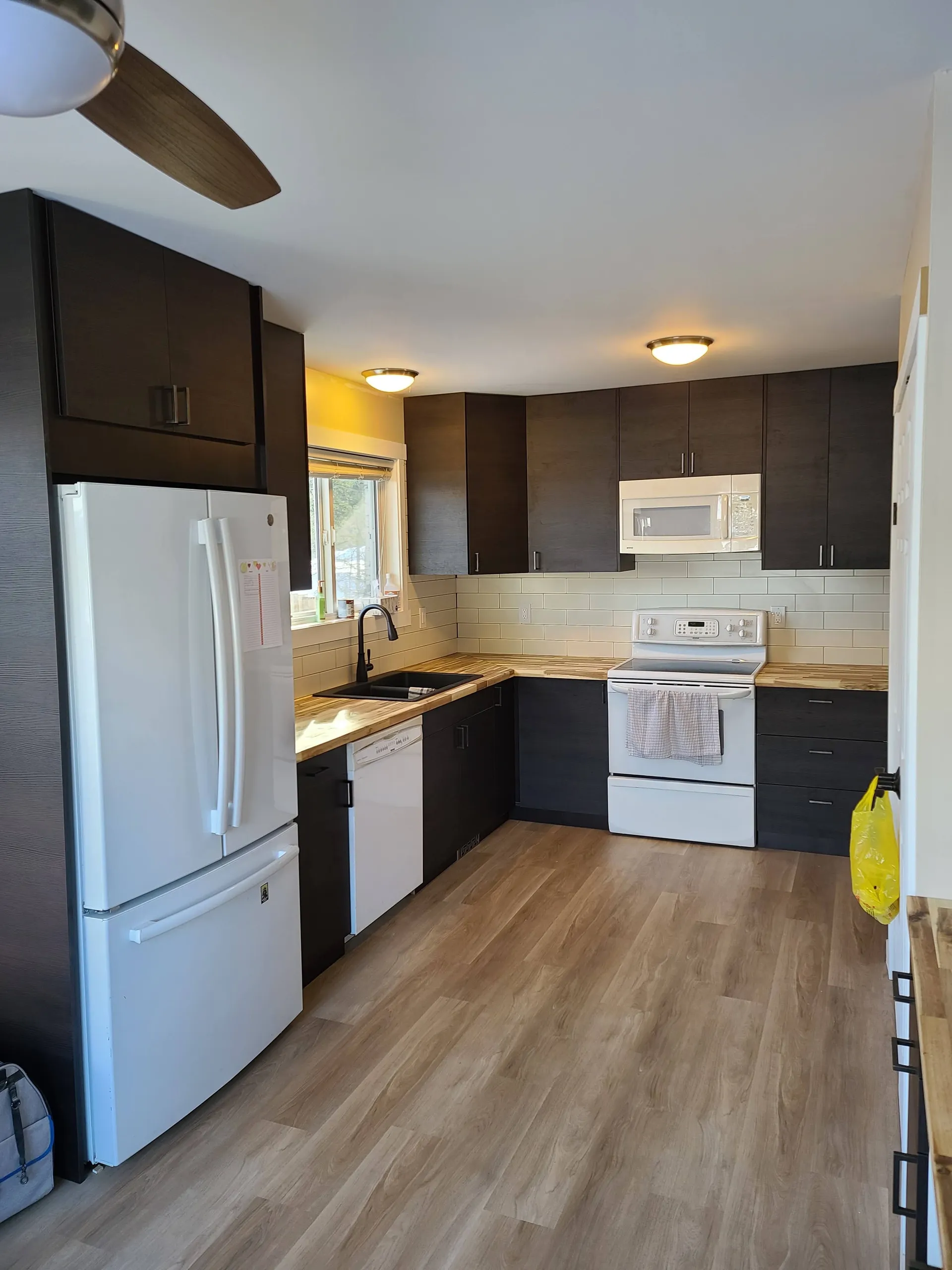 Finished kitchen with dark cabinets and light flooring