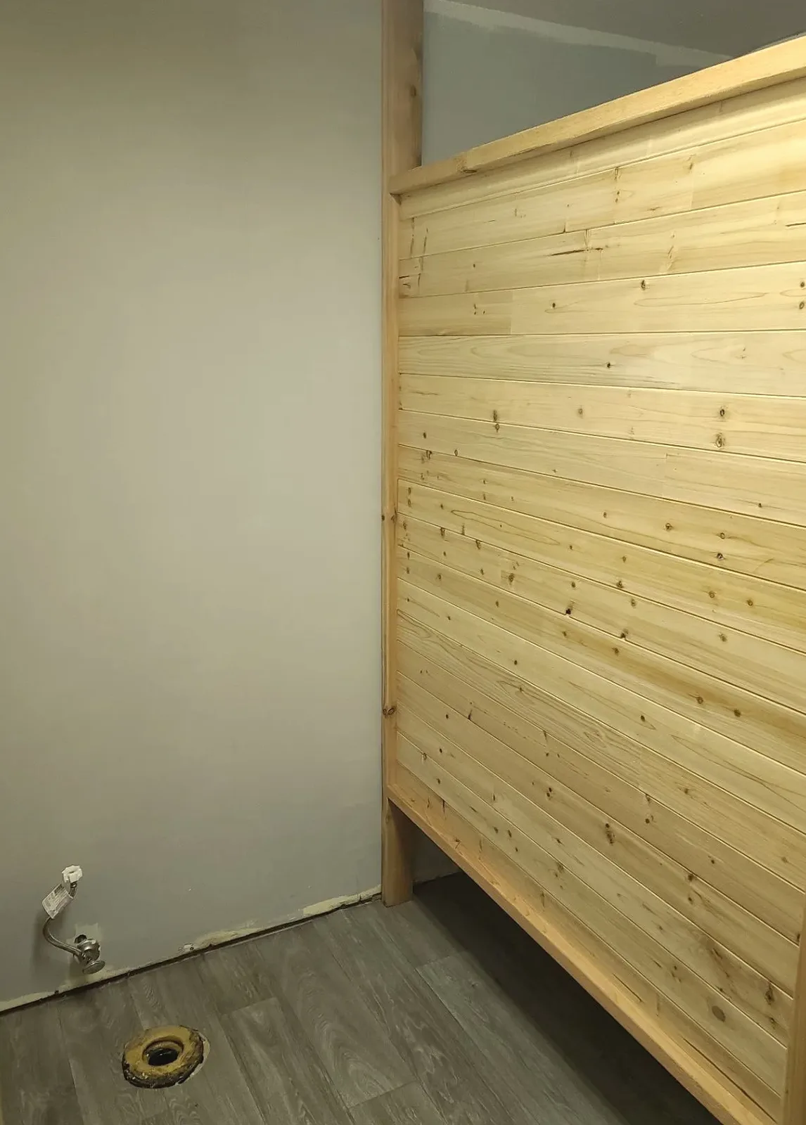 Residential interior with a wood-plank feature wall, installed flooring, and unfinished lower wall edge